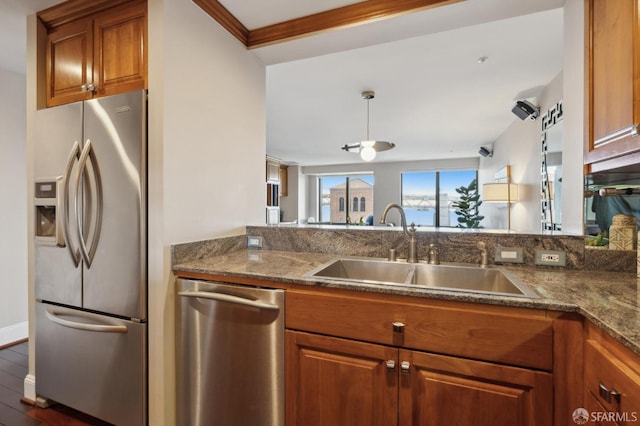 kitchen featuring dark stone countertops, sink, kitchen peninsula, and appliances with stainless steel finishes