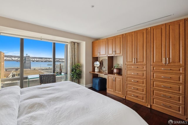 bedroom with a water view and dark hardwood / wood-style floors