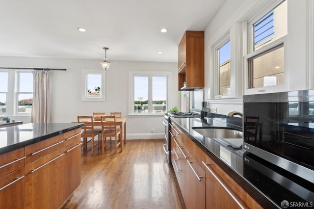 kitchen featuring stainless steel appliances, brown cabinetry, modern cabinets, and a sink