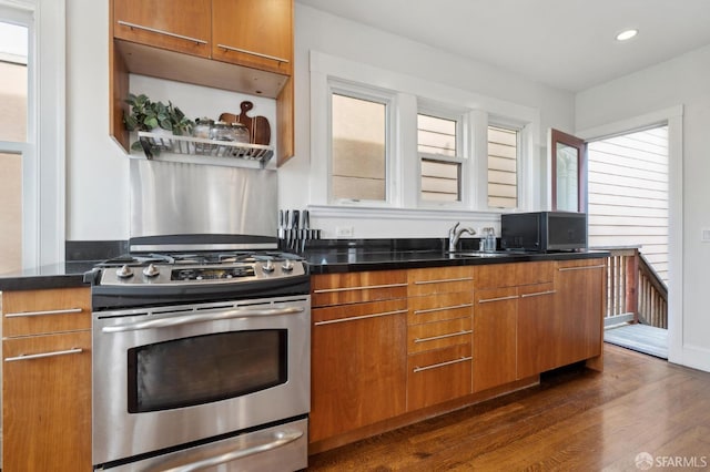 kitchen with dark countertops, brown cabinetry, dark wood-style flooring, and stainless steel range with gas stovetop