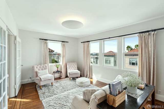 sitting room with a wealth of natural light, dark wood-style flooring, and baseboards