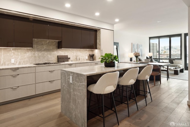 kitchen with tasteful backsplash, a kitchen island, stainless steel gas cooktop, and light hardwood / wood-style flooring