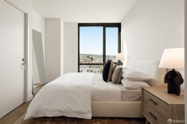 bedroom featuring expansive windows and dark hardwood / wood-style floors