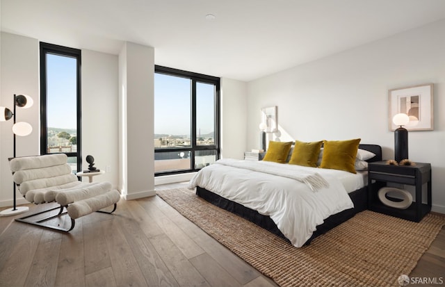 bedroom featuring a wall of windows and light hardwood / wood-style floors