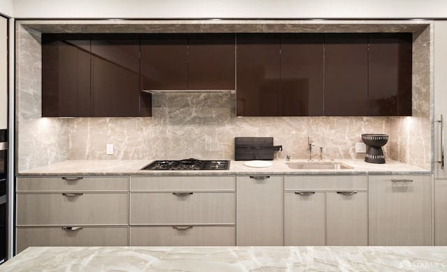 kitchen featuring backsplash, stainless steel gas cooktop, sink, and light stone counters