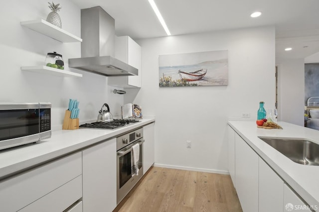 kitchen featuring stainless steel appliances, white cabinetry, light countertops, wall chimney range hood, and open shelves