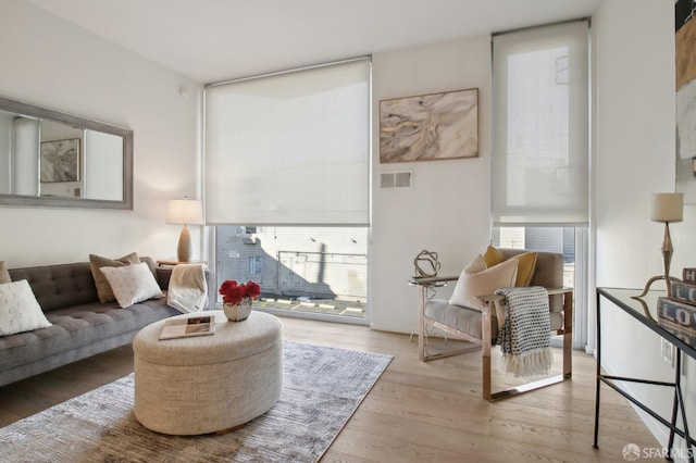 living room with visible vents, a wall of windows, and wood finished floors