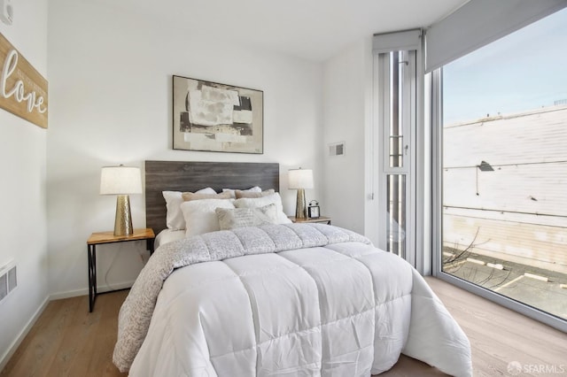 bedroom with access to outside, baseboards, and wood finished floors