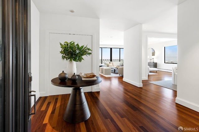 corridor featuring a baseboard radiator, baseboards, and dark wood-style flooring