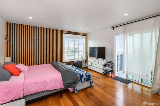 bedroom with access to exterior, recessed lighting, and wood finished floors