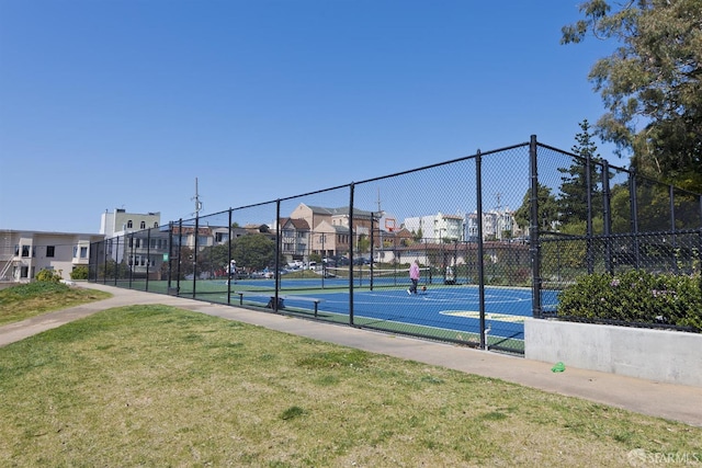 view of tennis court with community basketball court, a yard, fence, and a residential view