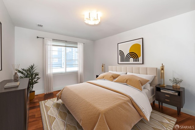 bedroom featuring visible vents, baseboards, and wood finished floors