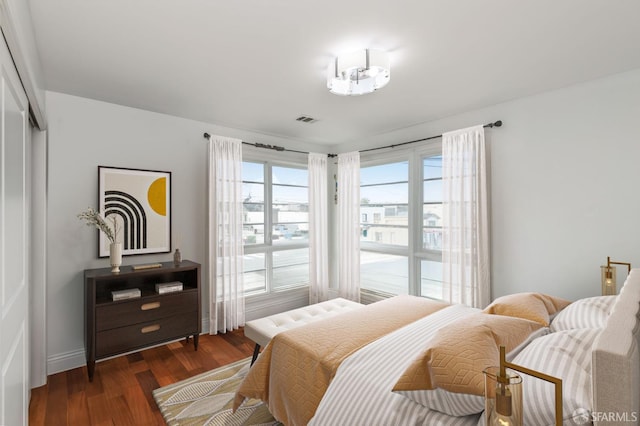 bedroom featuring a closet, visible vents, baseboards, and wood finished floors