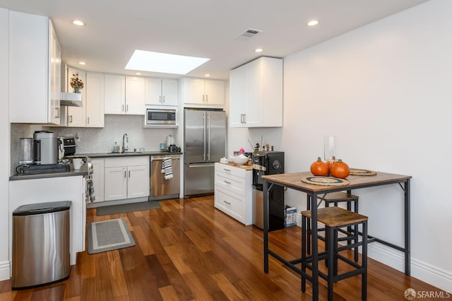 kitchen with visible vents, dark wood finished floors, appliances with stainless steel finishes, a skylight, and a sink