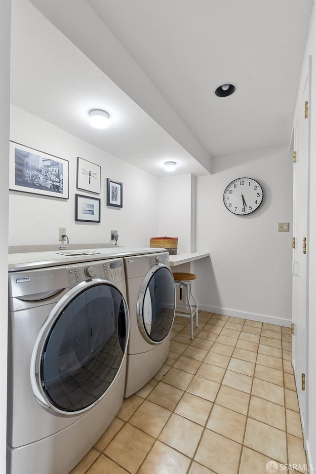 washroom featuring light tile patterned floors, washing machine and clothes dryer, laundry area, and baseboards