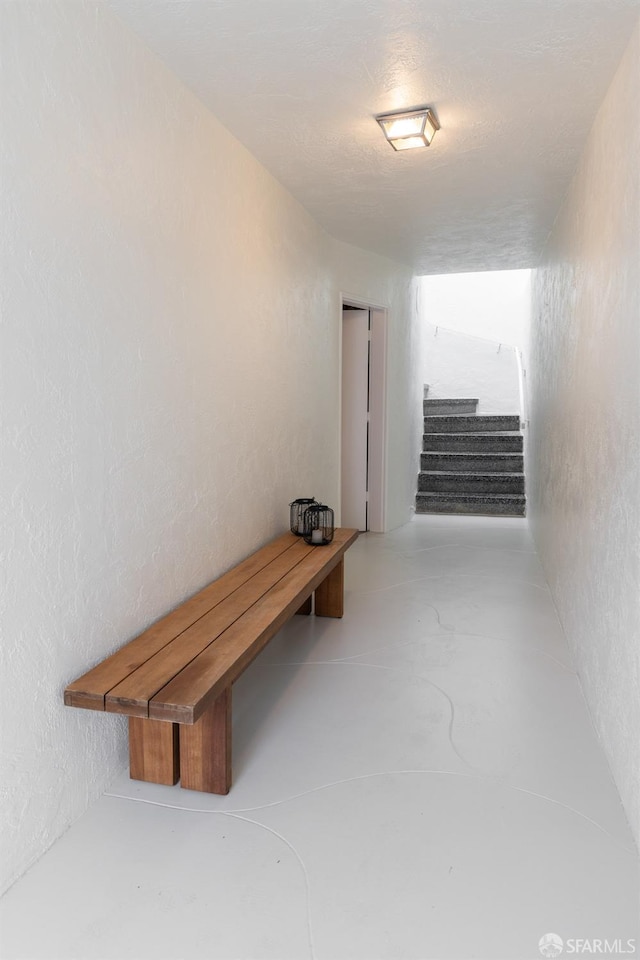 hall featuring stairway and a textured wall