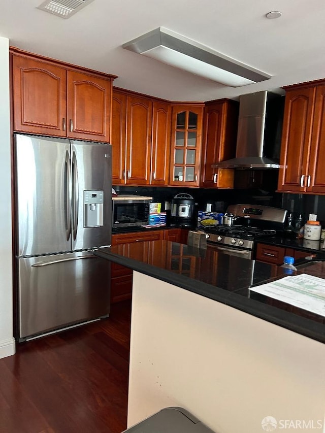 kitchen featuring wall chimney exhaust hood, kitchen peninsula, stainless steel appliances, and dark wood-type flooring