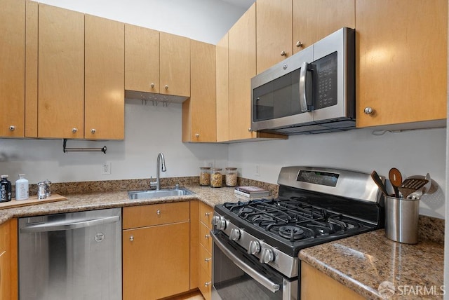 kitchen featuring stone counters, appliances with stainless steel finishes, and sink