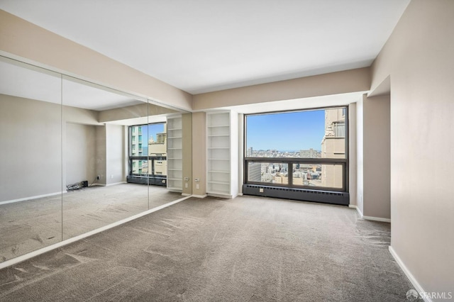 carpeted empty room featuring baseboard heating