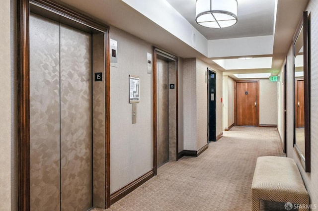 hallway featuring elevator and light colored carpet