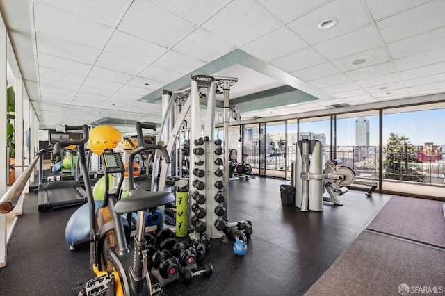 gym with a drop ceiling and a wall of windows