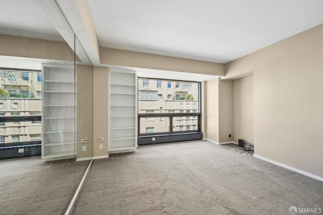 spare room with carpet flooring and a baseboard heating unit