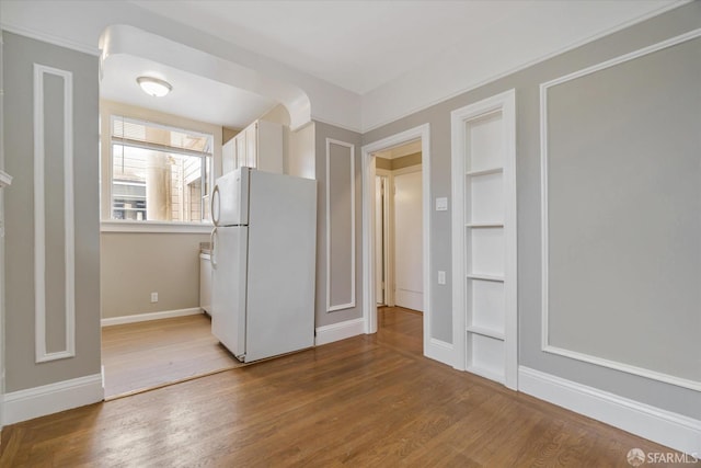 kitchen with white cabinetry, wood-type flooring, and white refrigerator