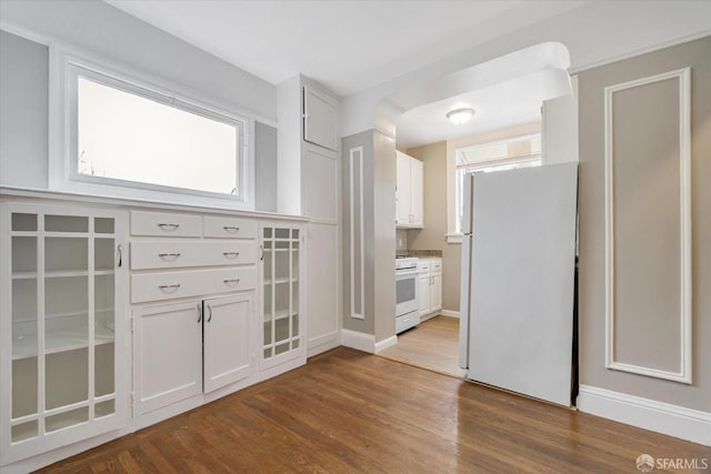 kitchen with hardwood / wood-style flooring, white cabinetry, a wealth of natural light, and white appliances