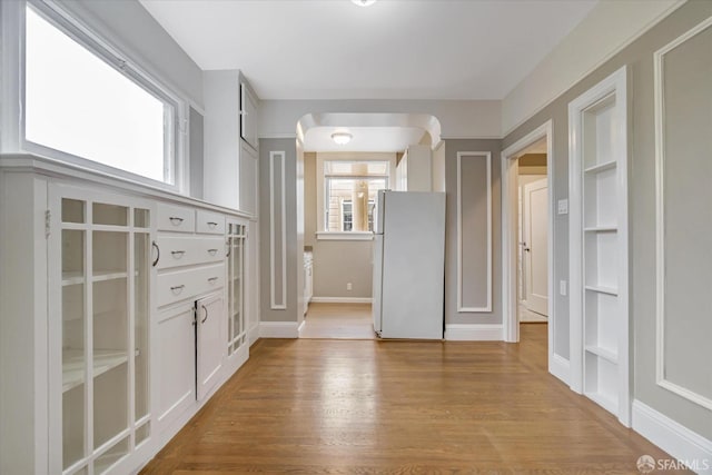 interior space featuring built in features, white fridge, and light wood-type flooring