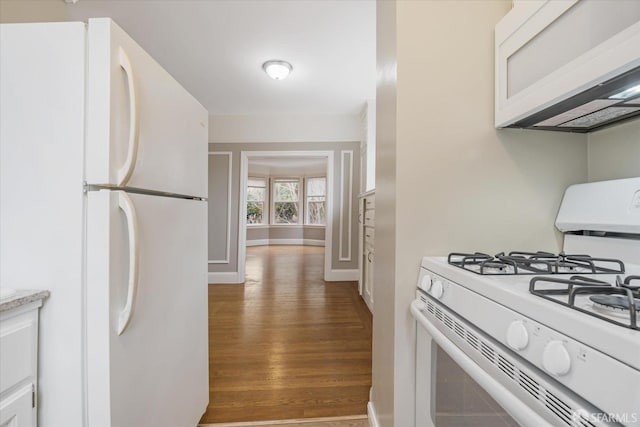 kitchen featuring white appliances, dark hardwood / wood-style floors, and white cabinets