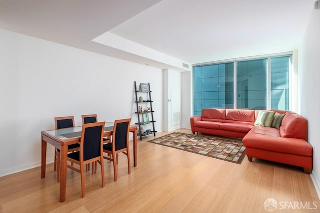 living room with a wall of windows and light wood-type flooring