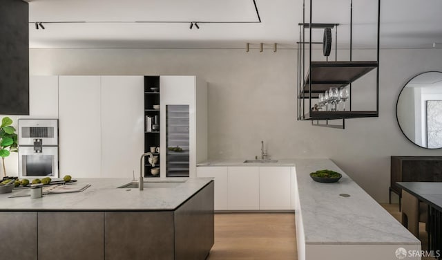 kitchen featuring white cabinetry, sink, and light stone countertops