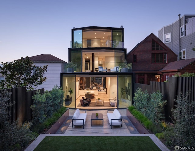 back house at dusk with an outdoor hangout area and a balcony