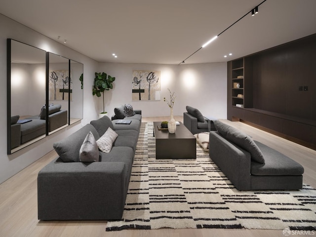 living room with built in shelves and light hardwood / wood-style flooring