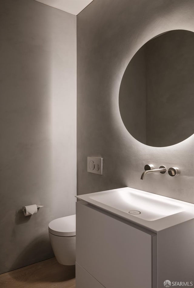 bathroom featuring vanity, hardwood / wood-style flooring, and toilet