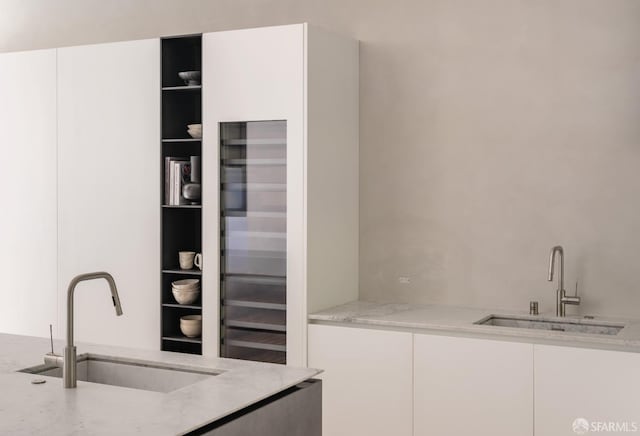 kitchen featuring white cabinetry, sink, and light stone countertops