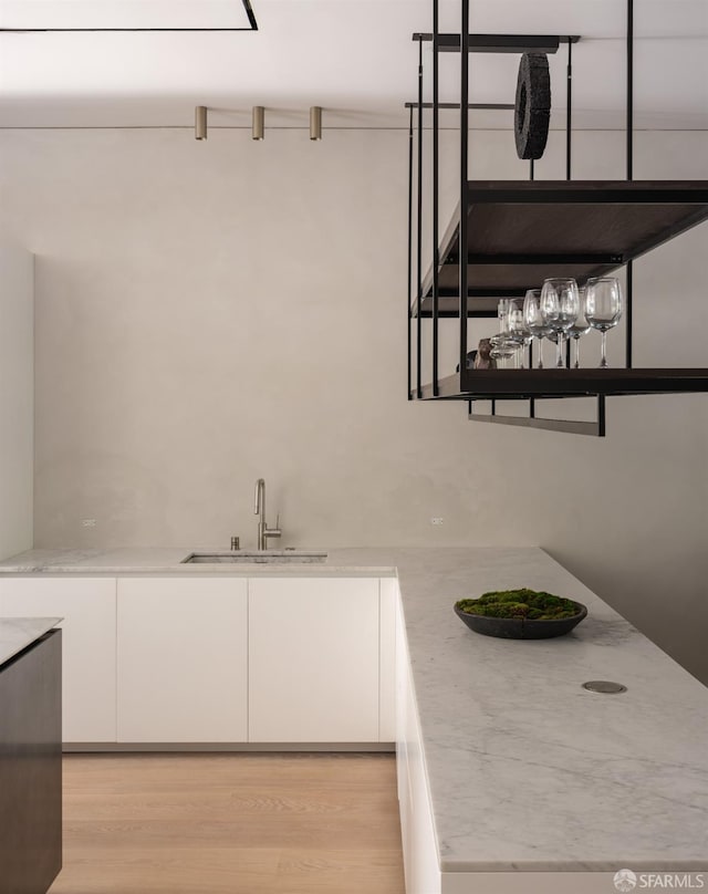 kitchen featuring light hardwood / wood-style floors, white cabinetry, and sink