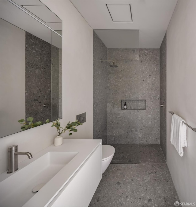 bathroom with vanity, toilet, and tiled shower