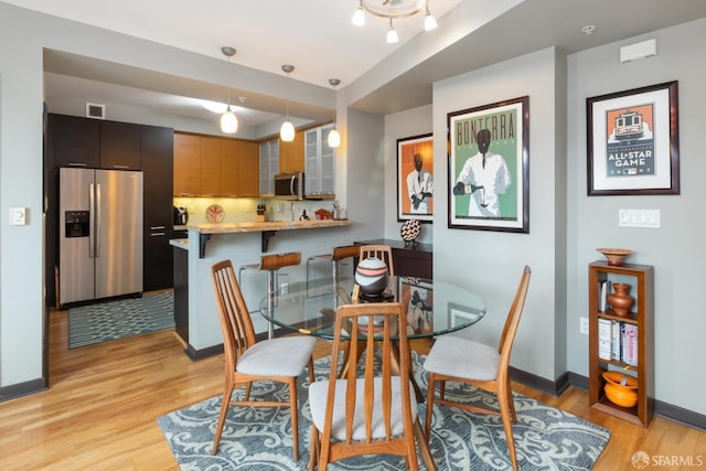 dining room featuring visible vents, baseboards, and light wood finished floors