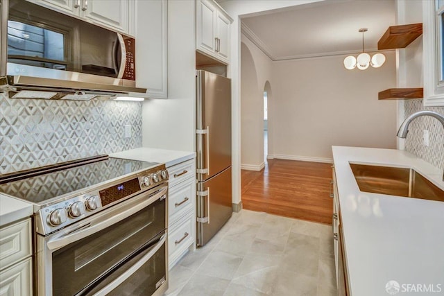 3675 Fillmore St Unit 102, San Francisco, CA 94123 - kitchen featuring stainless steel appliances, arched walkways, light countertops, a sink, and ornamental molding