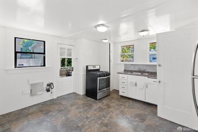 2875 Sunset Ave, Oakland, CA 94601 - kitchen featuring stainless steel range with gas cooktop, a sink, dark countertops, white cabinets, and stone finish floors