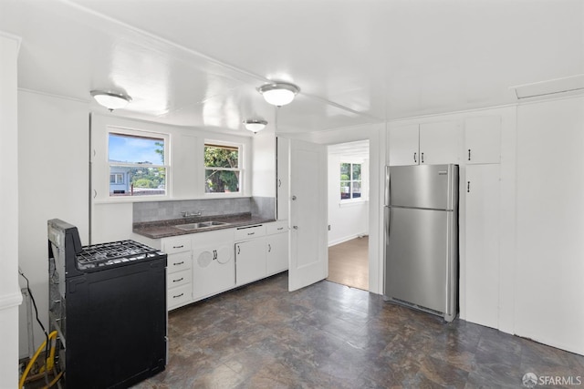 2875 Sunset Ave, Oakland, CA 94601 - kitchen with freestanding refrigerator, dark countertops, a sink, range with gas stovetop, and white cabinets