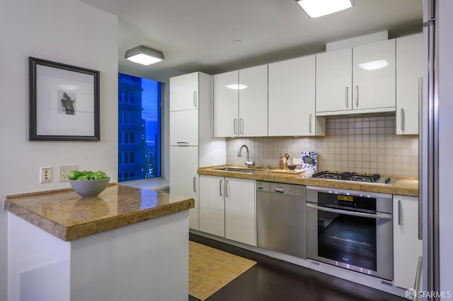 kitchen with white cabinetry, stainless steel appliances, tasteful backsplash, sink, and kitchen peninsula