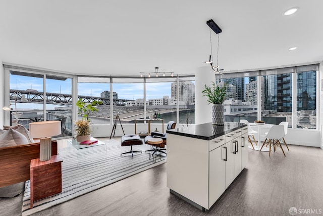 kitchen featuring dark countertops, wood finished floors, a view of city, white cabinetry, and a wealth of natural light