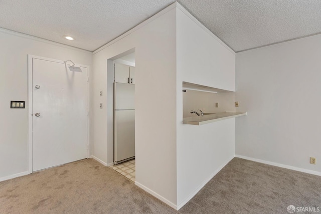 corridor featuring light carpet, baseboards, and a textured ceiling