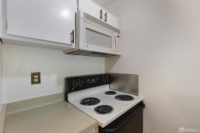 kitchen featuring light countertops, white microwave, range with electric stovetop, and white cabinets