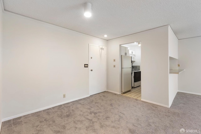 spare room with light carpet, baseboards, and a textured ceiling