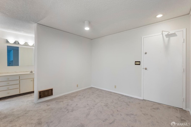 unfurnished bedroom with baseboards, ensuite bathroom, a textured ceiling, carpet floors, and recessed lighting