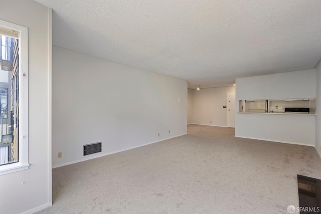 unfurnished living room featuring carpet floors, baseboards, visible vents, and a textured ceiling