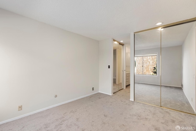 unfurnished bedroom featuring baseboards, a textured ceiling, carpet floors, a closet, and recessed lighting